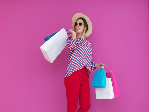 Giovane donna con le borse della spesa su sfondo rosa. Ragazza felice in posa con nuovi acquisti dopo una giornata di grande vendita. Concetto di venerdì nero