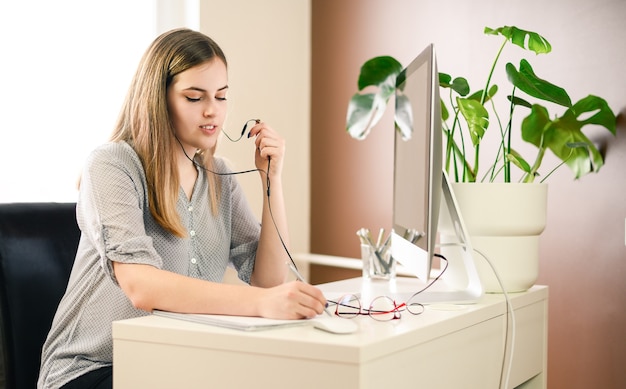 Giovane donna con le cuffie che lavorano, imparano, parlano al computer. Foto di alta qualità