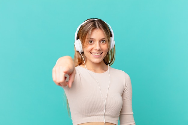 Giovane donna con le cuffie che punta alla telecamera scegliendo te