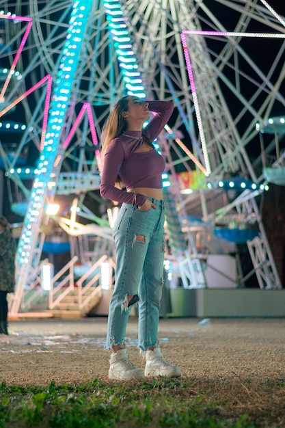 Giovane donna con le luci di una ruota panoramica sullo sfondo