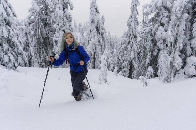 Giovane donna con le racchette da neve nella neve fresca