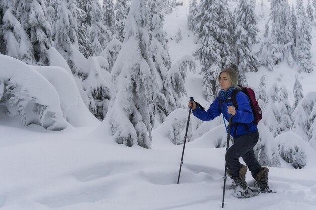 Giovane donna con le racchette da neve nella neve fresca