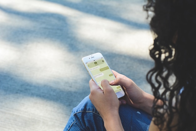 Giovane donna con lo smartphone che invia messaggio di testo