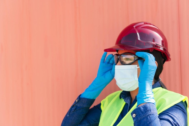 Giovane donna con maschera che indossa occhiali protettivi in una fabbrica