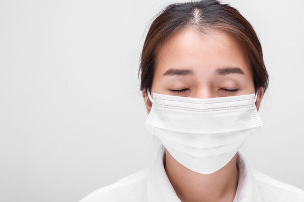 Giovane donna con maschera isolata su sfondo bianco per prevenire l'inquinamento atmosferico da coronavirus e PM 2.5, donna che dimostra come indossare una maschera protettiva anti-virus.