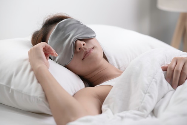 Giovane donna con maschera per gli occhi che dorme nel suo letto e si rilassa al mattino