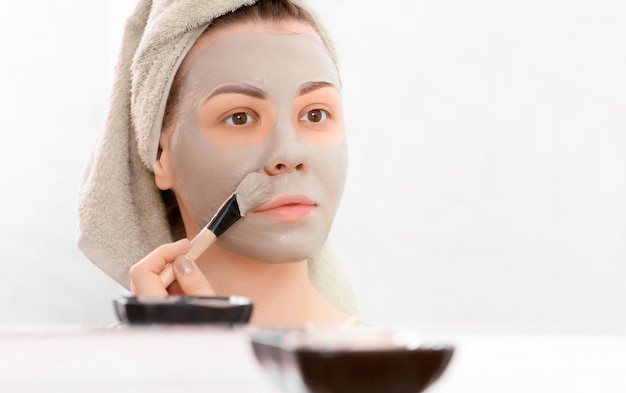 Giovane donna con maschera viso argilla.