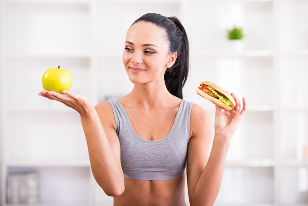 Giovane donna con mela e hot dog dopo aver esercitato a casa.