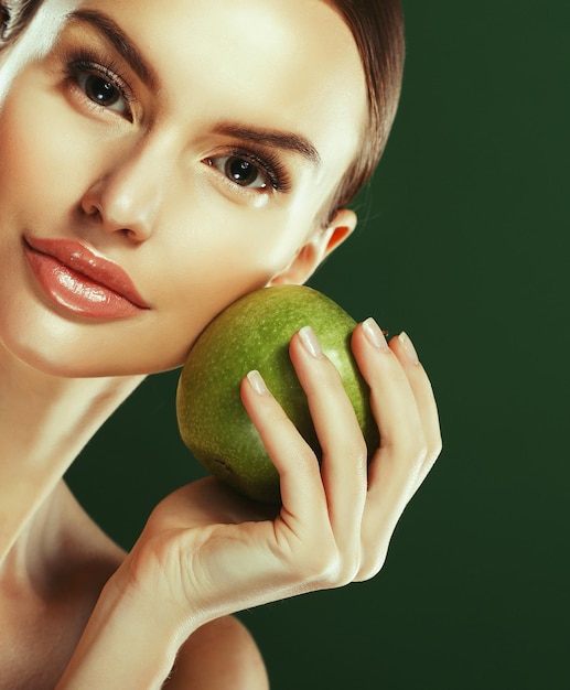 Giovane donna con mela verde su sfondo verde