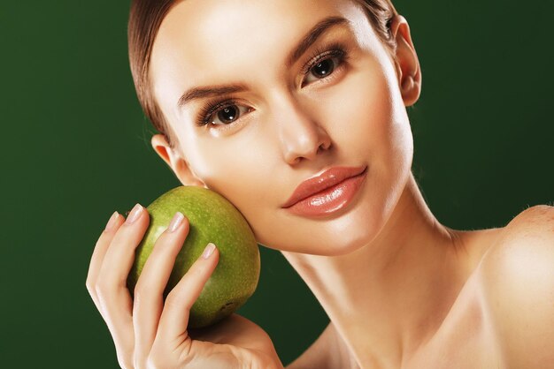 Giovane donna con mela verde su sfondo verde