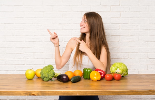 Giovane donna con molte verdure che punta il dito verso il lato