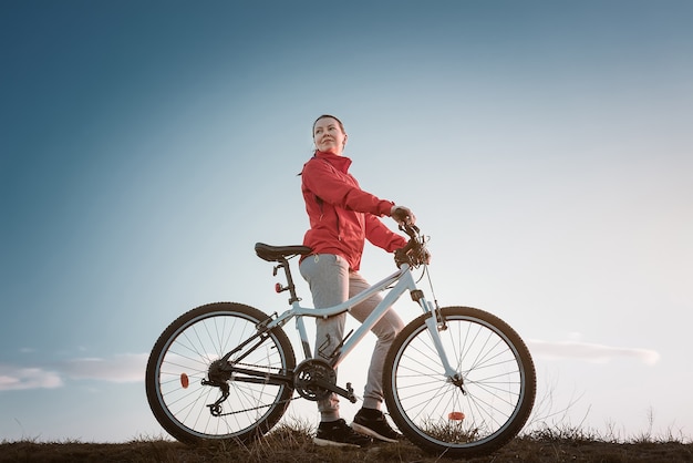 Giovane donna con mountain bike al tramonto.