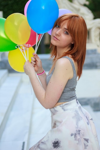 Giovane donna con palloncini colorati nel parco