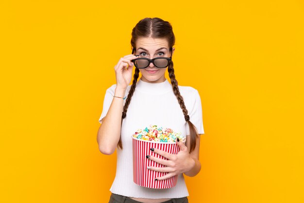 Giovane donna con popcorn sopra la parete isolata