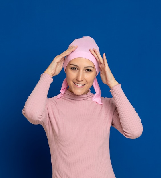 Giovane donna con sciarpa rosa sulla testa su un blu