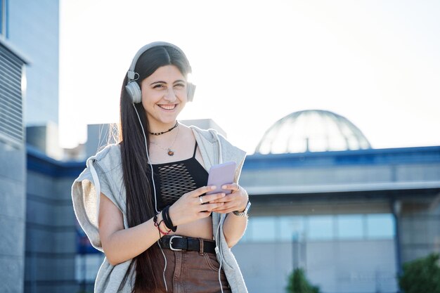 Giovane donna con smart phone all'aperto che indossa le cuffie