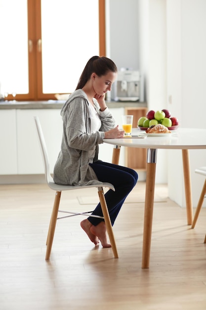 giovane donna con succo d'arancia e tablet in cucina