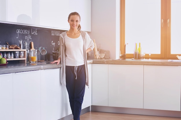 giovane donna con succo d'arancia e tablet in cucina