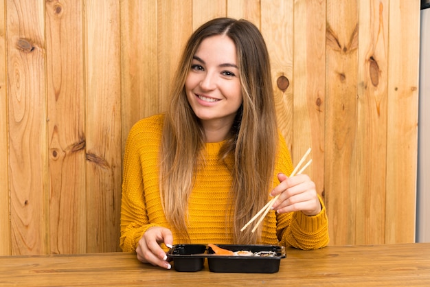 Giovane donna con sushi sulla parete di legno