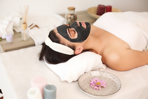 Giovane donna con trattamento maschera nera presso la spa