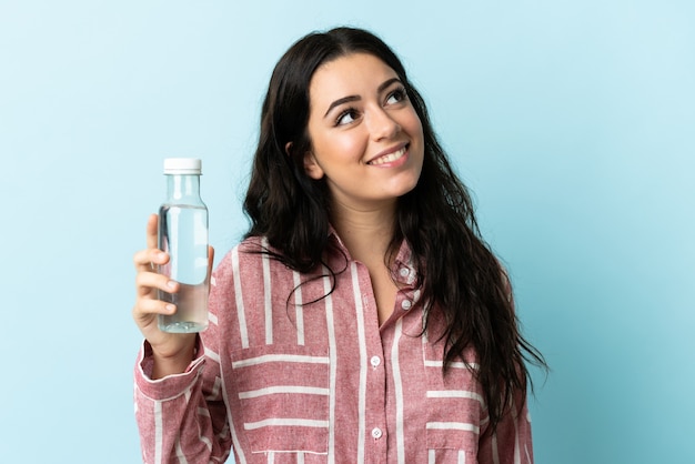 Giovane donna con un'acqua isolata che osserva in su mentre sorride