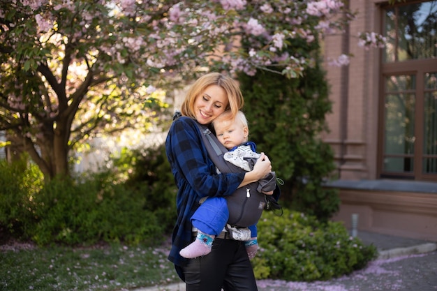 Giovane donna con un bambino in braccio felice Sakura fiorisce in primavera Parco Gioia della maternità e dello sviluppo del bambino Cherry Blossom Tree in tarda primavera