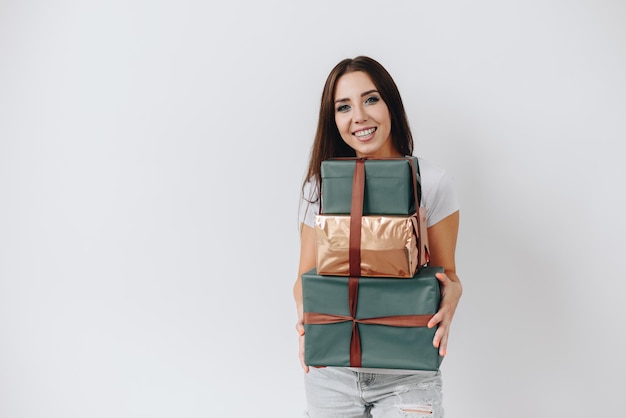 Giovane donna con un bel sorriso con scatole regalo di festa nelle sue mani Ragazza felice sul muro bianco