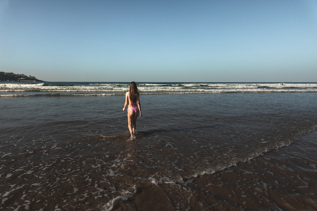 Giovane donna con un bikini rosa che va al mare