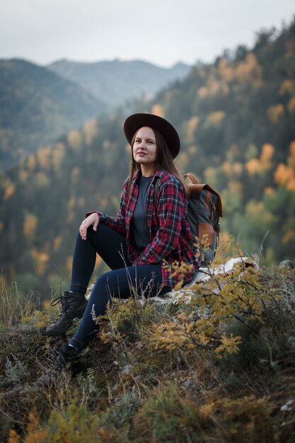 Giovane donna con un cappello sul picco di montagna