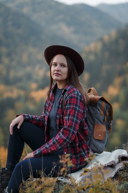 Giovane donna con un cappello sul picco di montagna