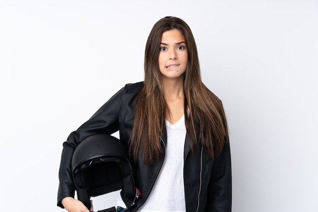 Giovane donna con un casco da motociclista sul muro bianco isolato con dubbi e con espressione del viso confuso