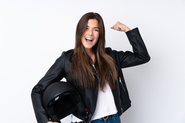 Giovane donna con un casco del motociclo sopra la parete bianca isolata che celebra una vittoria