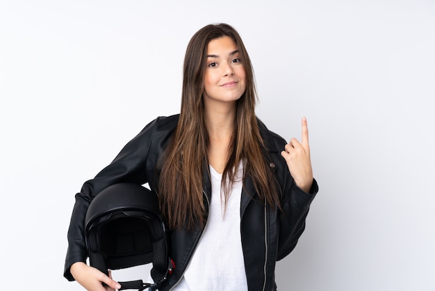 Giovane donna con un casco del motociclo sopra la parete bianca isolata che indica con il dito indice una grande idea
