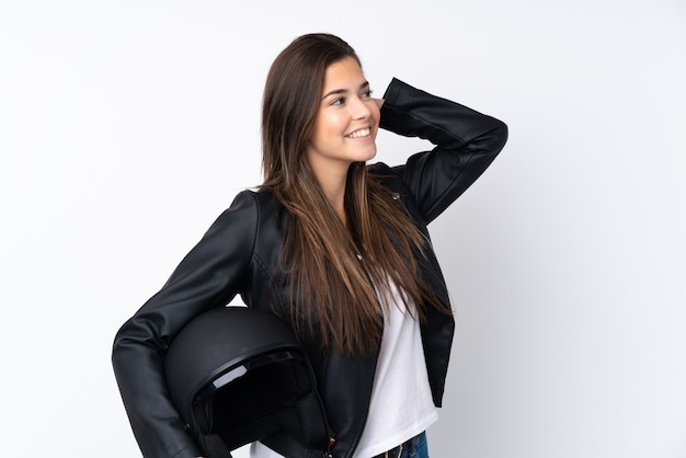 Giovane donna con un casco del motociclo sopra la risata bianca isolata della parete