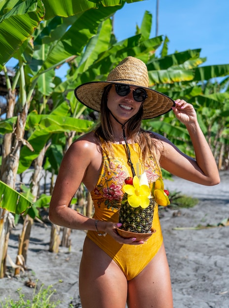Giovane donna con un cocktail in ananas sulle spiagge del Brasile nordorientale