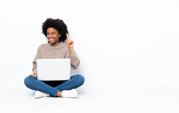 Giovane donna con un computer portatile seduto sul pavimento