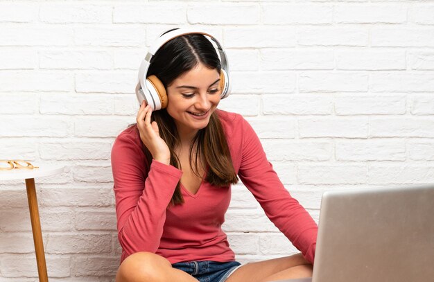 Giovane donna con un computer portatile seduto sul pavimento