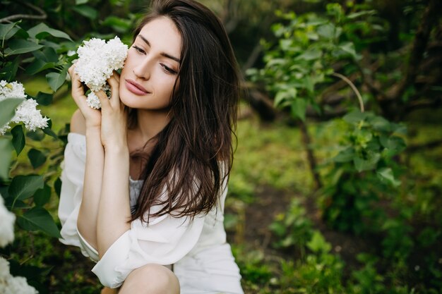 Giovane donna con un fiore lilla bianco