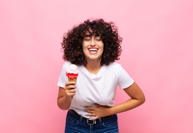 Giovane donna con un gelato che ride ad alta voce a uno scherzo esilarante, si sente felice e allegra, si diverte