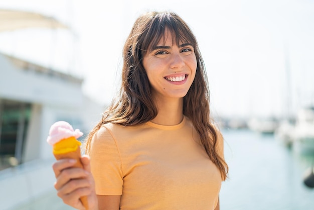 Giovane donna con un gelato di cornetta all'aperto che sorride molto