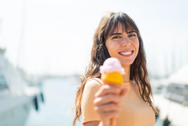 Giovane donna con un gelato di cornetta all'aperto con felice espressione