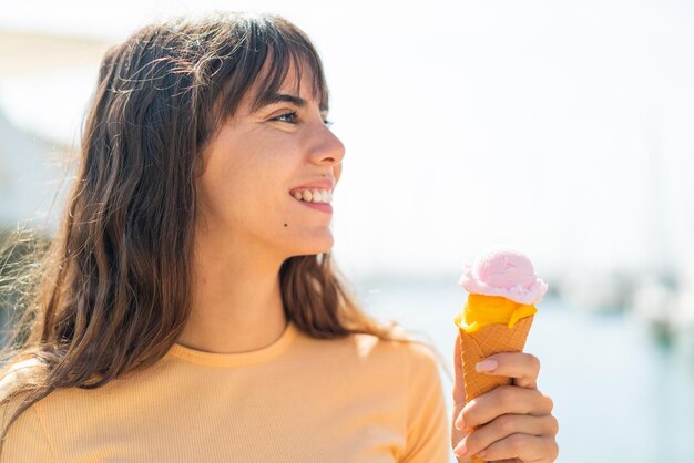 Giovane donna con un gelato di cornetta all'aperto