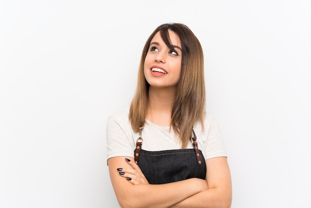 Giovane donna con un grembiule che osserva in su mentre sorridendo