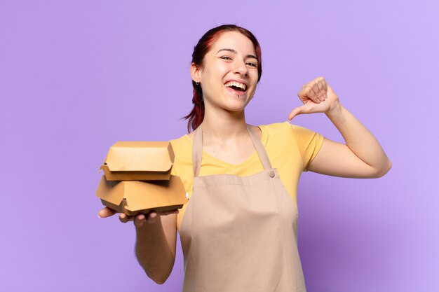 Giovane donna con un grembiule e portare via hamburger