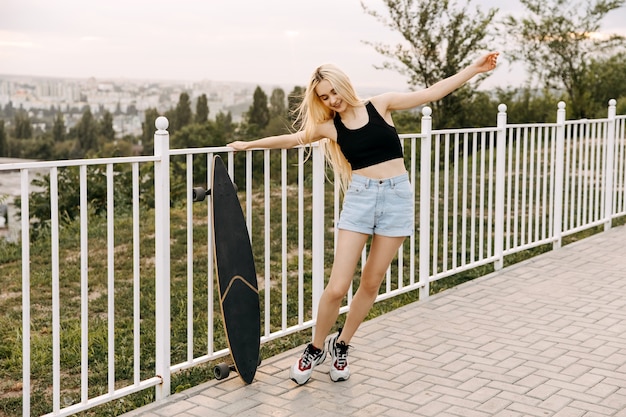 Giovane donna con un longboard, all'aperto