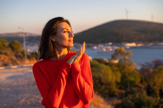 Giovane donna con un maglione rosso in un magnifico tramonto sulla montagna