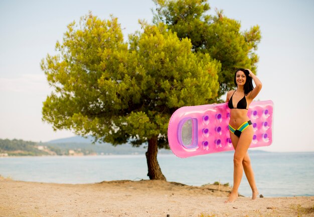 Giovane donna con un materasso sulla spiaggia