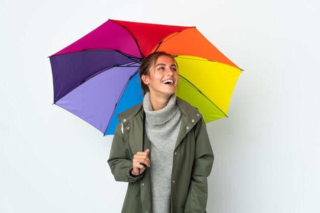 Giovane donna con un ombrello su sfondo bianco ridendo