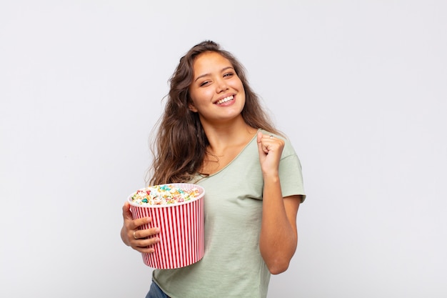 Giovane donna con un secchio pop conrs che si sente felice, positiva e di successo, motivata quando affronta una sfida o celebra buoni risultati