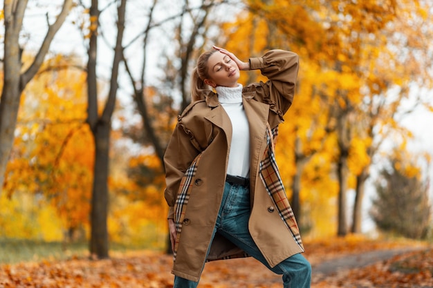 giovane donna con un taglio di capelli alla moda in un cappotto elegante pone all'aperto in un parco